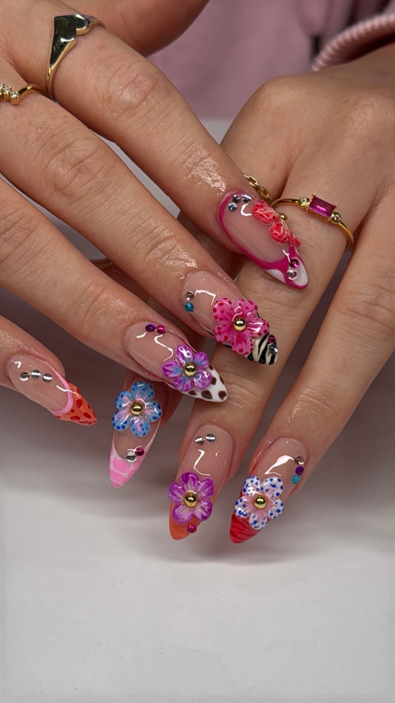 Vibrant pink and purple floral nails with gems